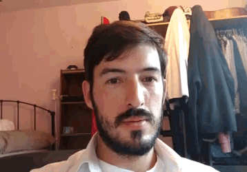 a man with a beard is wearing a white shirt with the letter s on the front