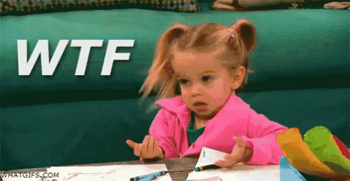 a little girl in a pink jacket is sitting at a table with the word wtf written on it .