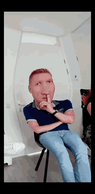 a man is sitting in a chair with his hand to his mouth