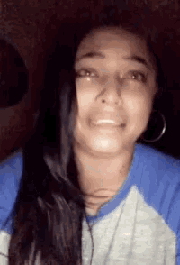 a woman with long hair is wearing a blue and grey shirt