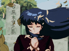 a girl with long black hair is praying in front of a grave