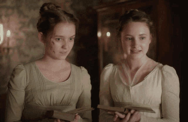 two women in white dresses holding books in their hands