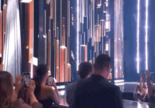 a group of people are taking pictures of a stage with their cell phones .