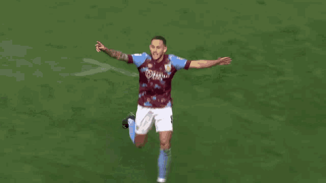 a soccer player wearing a purple shirt and blue shorts is walking on a field .