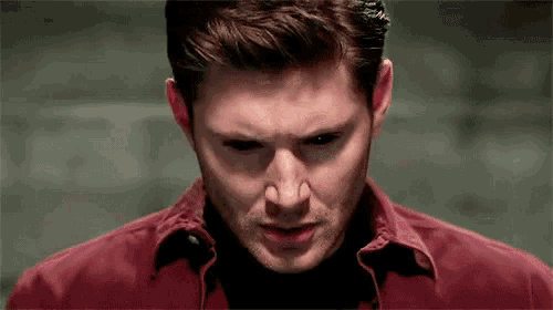 a man in a red shirt is looking at the camera with his eyes glowing .