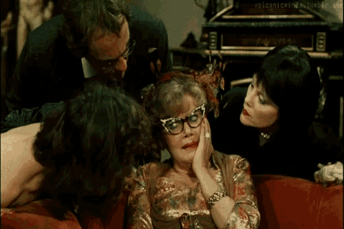 a group of people sitting around a woman with glasses