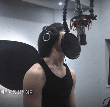 a man wearing headphones singing into a microphone with korean writing on the bottom