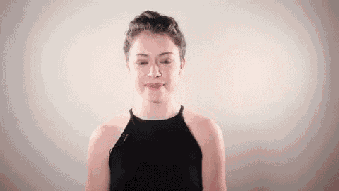 a young woman in a black tank top is making a funny face and smiling .