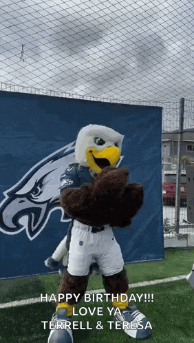 a mascot is standing in front of a sign that says `` happy birthday '' .