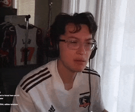 a young man wearing glasses and headphones is sitting in front of a computer screen .