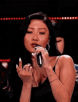 a woman is singing into a microphone while another woman watches .