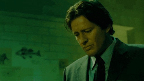 a man in a suit and tie is standing in a dark room