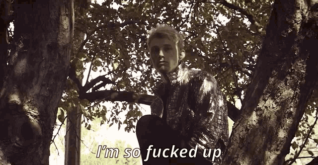 a man sitting in a tree with the words " i 'm so fucked up " written below him