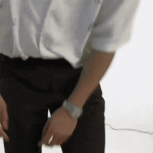 a man in a white shirt and black pants has a watch on his wrist ..