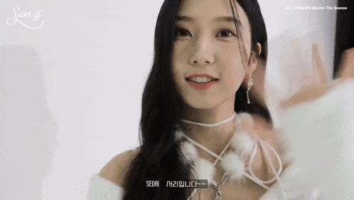 a close up of a woman wearing a white sweater and a white choker .