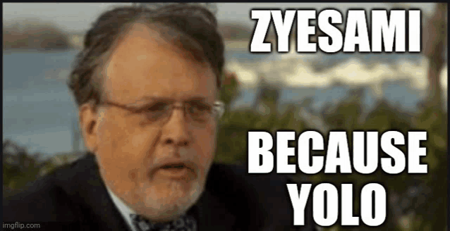 a man with glasses and a beard says zyesami because yolo in front of a body of water .
