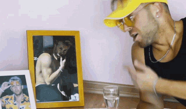 a man wearing a yellow hat and sunglasses talks to another man