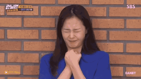 a woman is making a face in front of a brick wall .
