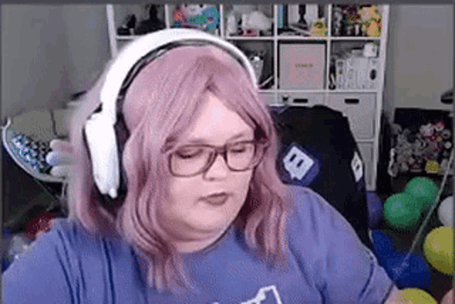 a woman wearing headphones and glasses is sitting in a room with balloons .