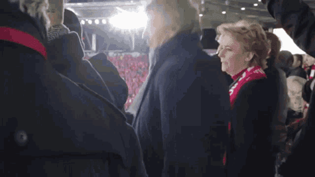 a woman wearing a scarf that says ' hillary clinton ' on it stands in a crowd