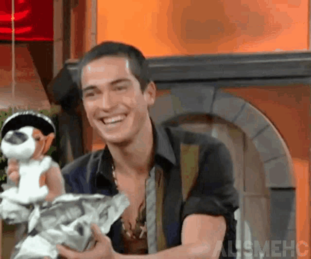 a man is smiling while holding a stuffed animal and a piece of paper ..