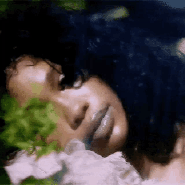 a close up of a woman 's face with a flower in the background .