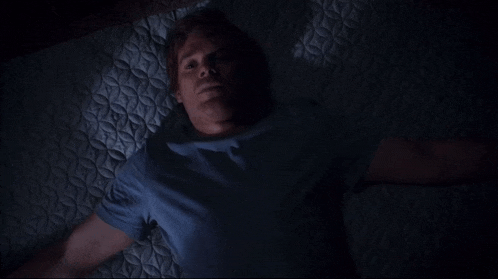 a man in a blue shirt is laying on a bed