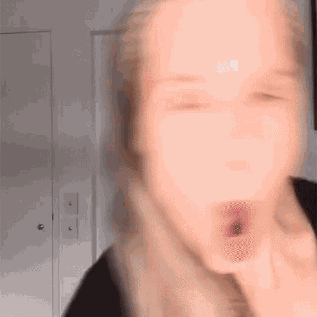 a blurry photo of a woman 's face with her eyes closed and her mouth open .