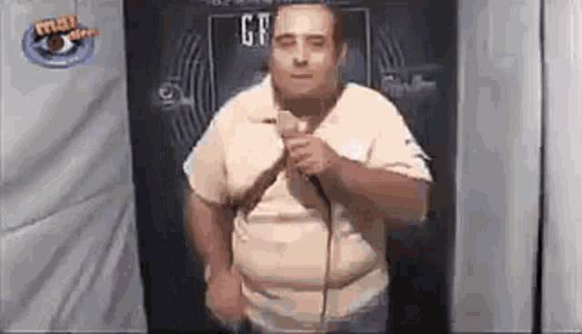 a man is holding a microphone in front of a blackboard with the word gf on it .