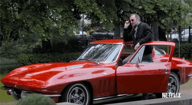 a man is standing next to a red car that says netflix on it