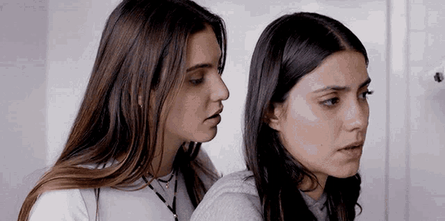 two women are standing next to each other and looking at each other .