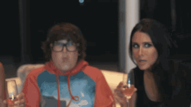 a woman is holding a glass of wine next to a boy who is wearing glasses