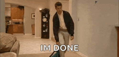 a man is walking down a hallway carrying a bag and saying `` i 'm done '' .
