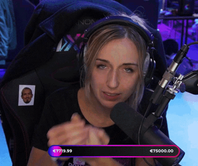 a woman wearing headphones is sitting in front of a microphone with a bar that says 7719.99 on it