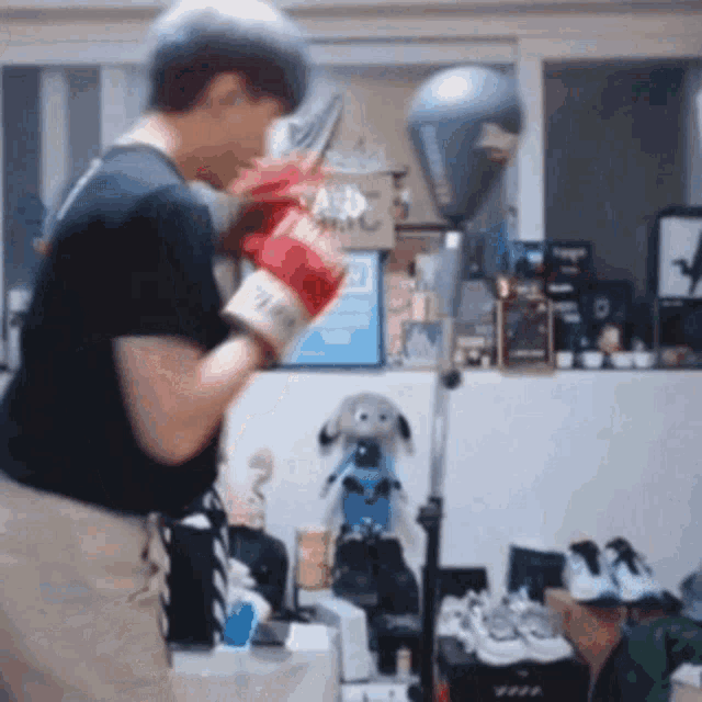 a man wearing red boxing gloves is standing in front of a punching bag in a room .