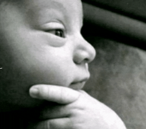 a close up of a baby 's face with a hand on his chin