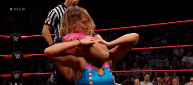 a woman with pink hair is in a wrestling ring