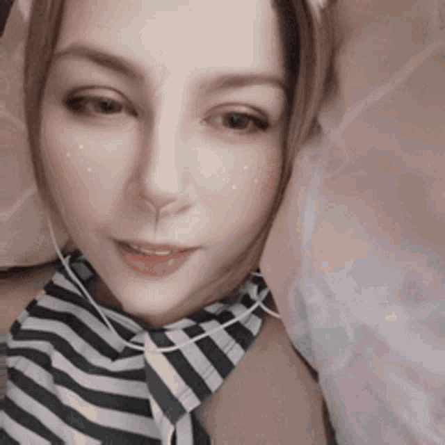 a woman wearing a striped shirt and tie is laying in bed