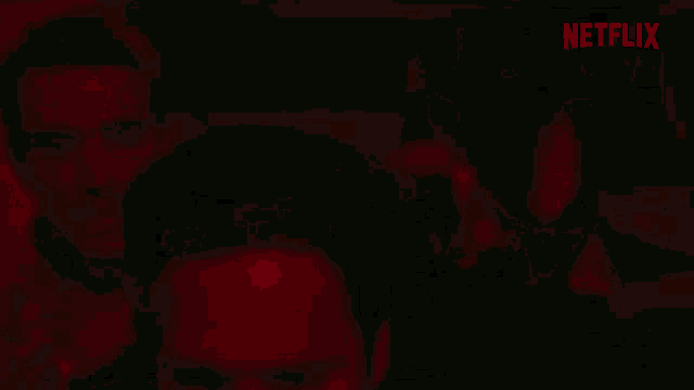 two men are standing next to each other in a dark room with a netflix logo in the background .