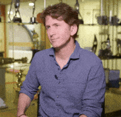 a man wearing a blue shirt is sitting in front of a glass display of trophies