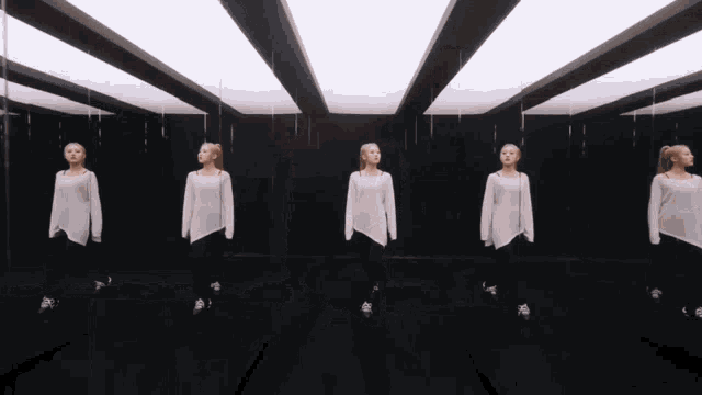 a row of women are standing in a room with mirrors
