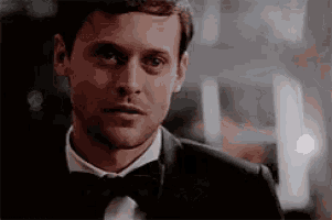 a man in a tuxedo and bow tie is looking at the camera .