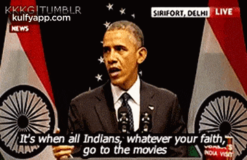 barack obama is giving a speech in front of an indian flag and says it 's when all indians go to the movies