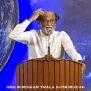 a man with a beard is standing at a podium holding a microphone and scratching his head .