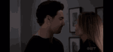 a man and a woman are kissing in front of a wall of pictures .