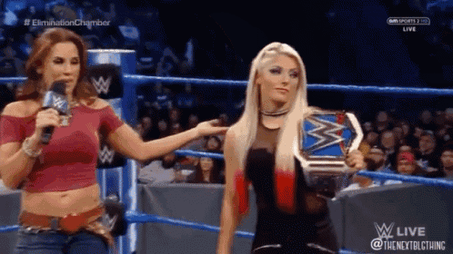two women in a wrestling ring one is holding a championship belt