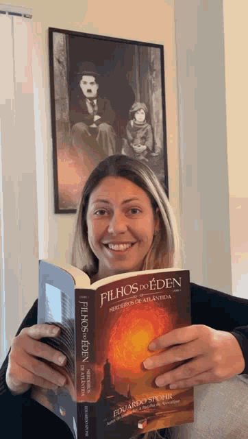 a woman holds a book titled filhos do eden