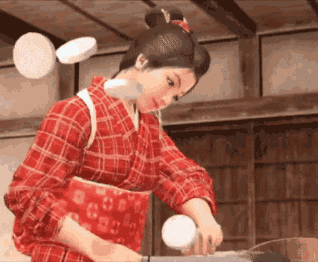 a woman in a red plaid shirt is cutting a piece of food