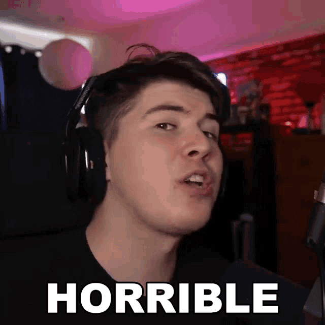 a man wearing headphones says horrible in front of a mic