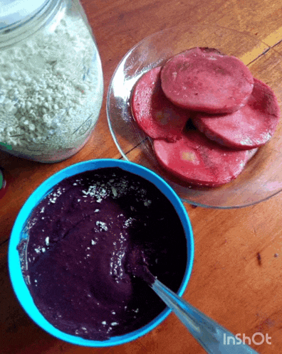 a blue bowl with a spoon in it sits next to a plate of red meat